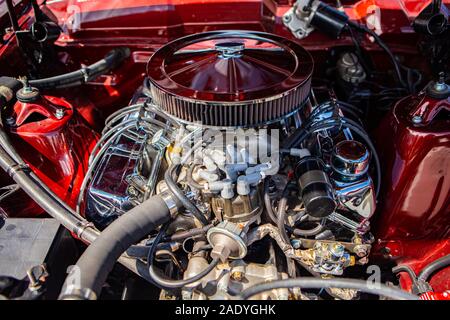 red classic muscle car under the hood, v8 engine with big chromed round air intake filter, tubes, wires, pipes, mechanical and electrical other parts Stock Photo