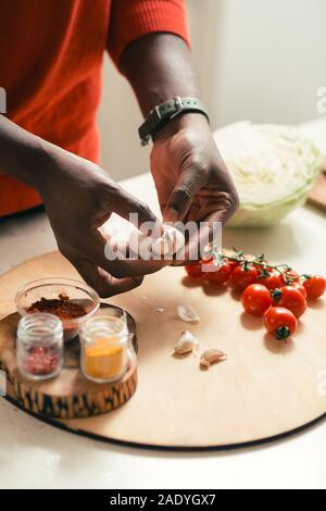 Hands of man holding cloves of garlic above the cutting board Stock Photo