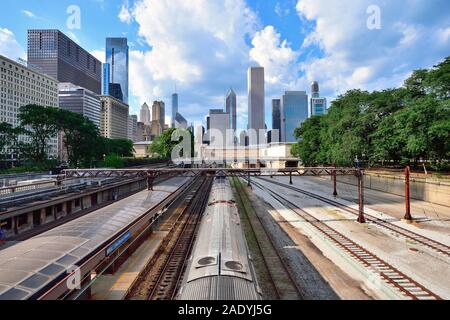 Chicago, Illinois, USA. Commuter train arriving at Van Buren Street Station with a segment of the city skyline towering above in the background.