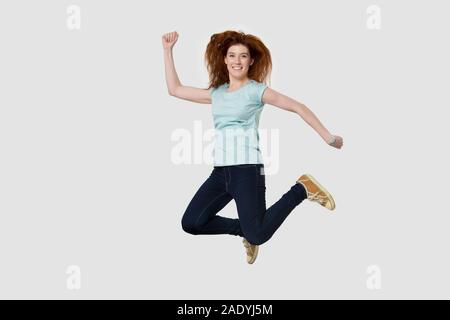 Overjoyed young happy red-haired woman jumping high. Stock Photo