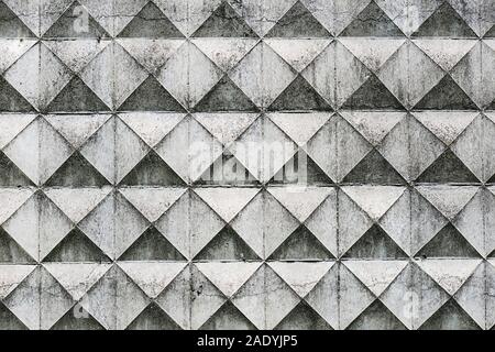 Part of a light concrete fence with rhombuses. White relief concrete wall with geometric shapes. Stock Photo