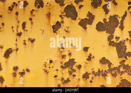 Close-up of weathered yellow painted metal surface with large and small rusty spots. Stock Photo