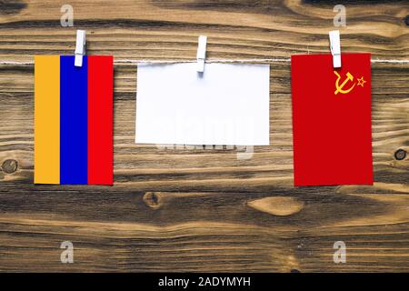 Hanging flags of Armenia and Soviet Union attached to rope with clothes pins with copy space on white note paper on wooden background.Diplomatic relat Stock Photo