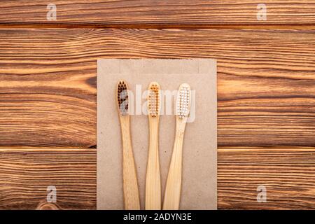 Bamboo toothbrushes on craft bag on wooden background.Flat lay with copy space.Natural bath products. Biodegradable natural bamboo toothbrush.Eco Stock Photo
