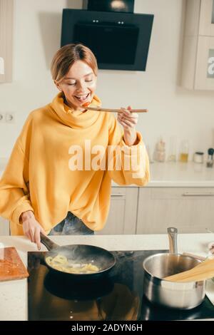 Excited woman closing eyes and smiling while tasting food Stock Photo