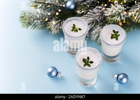 Winter holiday home made creamy cocktail, white milky liquer or eggnog on blue trendy background with festive decorations Stock Photo