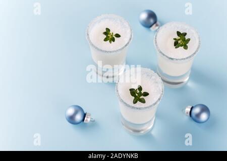 Winter holiday home made creamy cocktail, white milky liquer or eggnog on blue trendy background with festive decorations Stock Photo