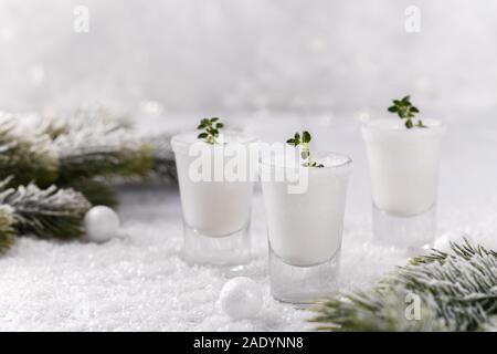Winter holiday home made creamy cocktail, white milky liquer or eggnog on snow with decorations Stock Photo