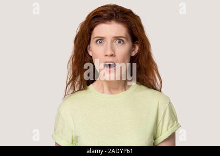 Studio portrait negatively surprised young red-haired woman. Stock Photo
