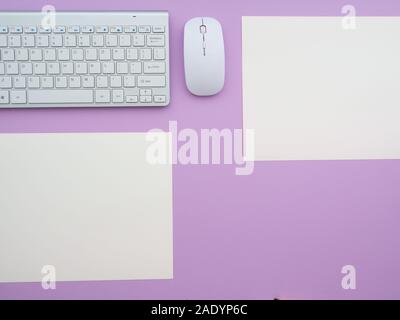 Keyboard and mouse and a blank two paper notes isolated on a purple background. Flat lay, top view copy space. Feminine workplace concept. Stock Photo