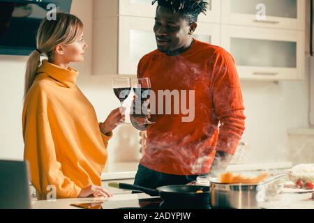 Young couple looking relaxed while drinking wine in the kitchen Stock Photo
