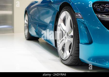 Close up front of new blue car with Magnesium alloy wheel parking on car showroom. Dealership office or retail shop and technology and business concep Stock Photo