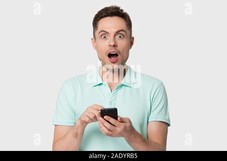 Portrait of surprised young man holding smartphone. Stock Photo