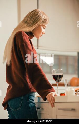 Long haired woman looking at the glass of wine on the table Stock Photo