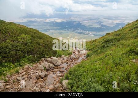 A small stream flows from the mountain lake in the High Tatra Mountains and flows into the valley. Slovakia Stock Photo