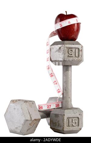 A pair of old free weights with a red delicious apple on top and a measuring tape wrapped around both. Isolated on white.