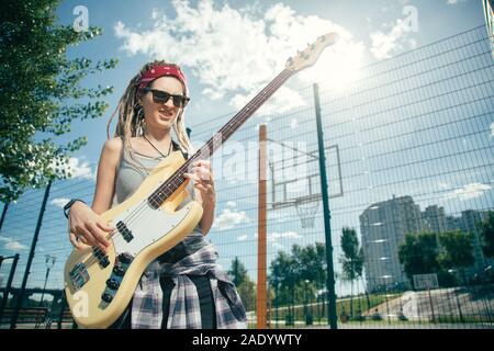 Expressive lady enjoying playing the guitar while being in the yard Stock Photo