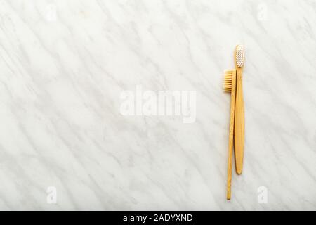 Bamboo toothbrushes on white marble background. Flat lay with copy space. Natural bath products. Biodegradable natural bamboo toothbrush. Eco friendly Stock Photo