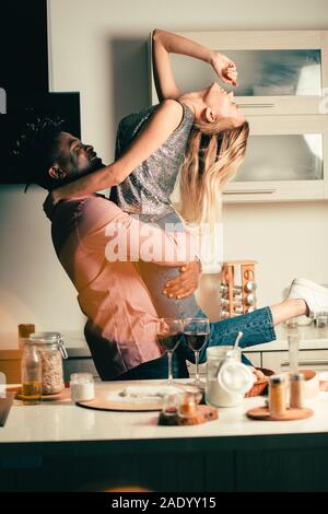 Happy lady throwing her head back while being in arms of boyfriend Stock Photo