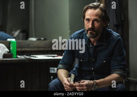 Close up of serious man sitting and holding barber instruments Stock Photo