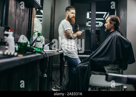 Curious man looking at his barber while sitting in the armchair Stock Photo
