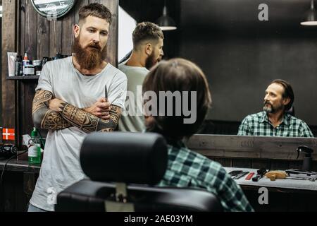 Dark haired man looking at the barber while sitting in armchair Stock Photo