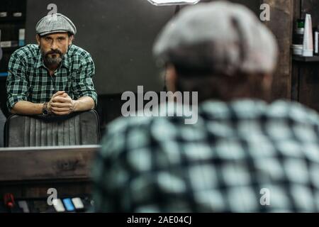 Serious bearded man looking at his reflection and frowning Stock Photo
