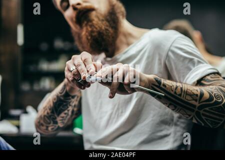Close up of bearded man sitting and holding his scissors Stock Photo