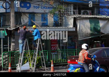 Bangkok, Thailand - December 4, 2019 : Two workers on ladders, they are installing new aluminum roof for the shop Stock Photo