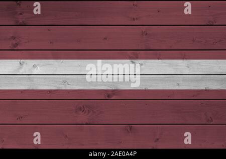 Latvia flag depicted in bright paint colors on old wooden wall close up. Textured banner on rough background Stock Photo