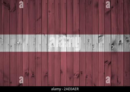 Latvia flag depicted in bright paint colors on old wooden wall close up. Textured banner on rough background Stock Photo