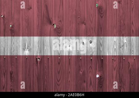 Latvia flag depicted in bright paint colors on old wooden wall close up. Textured banner on rough background Stock Photo