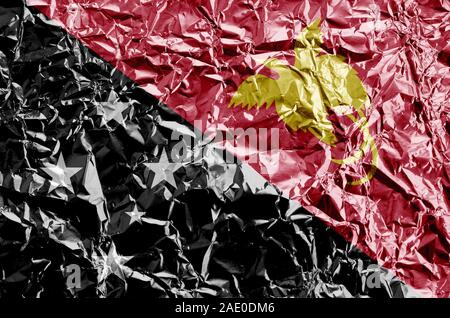 Papua New Guinea flag depicted in paint colors on shiny crumpled aluminium foil close up. Textured banner on rough background Stock Photo