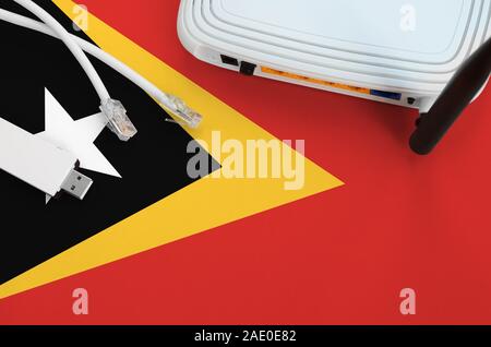 Timor Leste flag depicted on table with internet rj45 cable, wireless usb wi-fi adapter and router. Internet connection concept Stock Photo