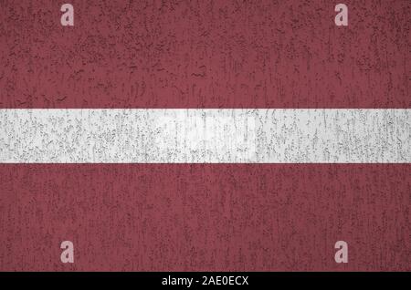 Latvia flag depicted in bright paint colors on old relief plastering wall close up. Textured banner on rough background Stock Photo