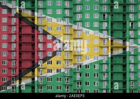 Guyana flag depicted in paint colors on multi-storey residental building under construction. Textured banner on big brick wall background Stock Photo