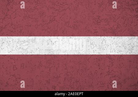 Latvia flag depicted in bright paint colors on old relief plastering wall close up. Textured banner on rough background Stock Photo