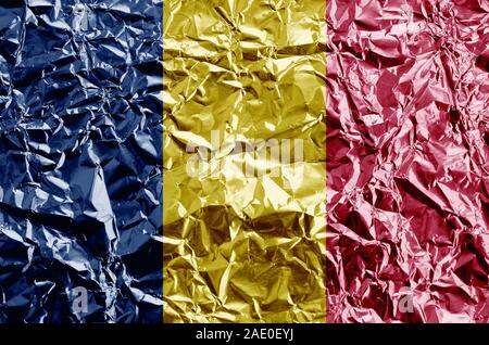 Chad flag depicted in paint colors on shiny crumpled aluminium foil close up. Textured banner on rough background Stock Photo