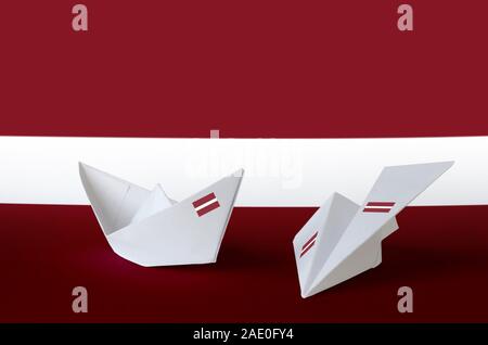 Latvia flag depicted on paper origami airplane and boat. Oriental handmade arts concept Stock Photo