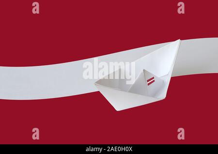 Latvia flag depicted on paper origami ship closeup. Oriental handmade arts concept Stock Photo