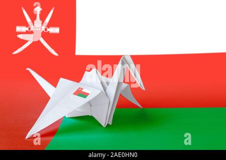 Oman flag depicted on paper origami crane wing. Oriental handmade arts concept Stock Photo