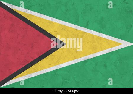 Guyana flag depicted in bright paint colors on old relief plastering wall close up. Textured banner on rough background Stock Photo