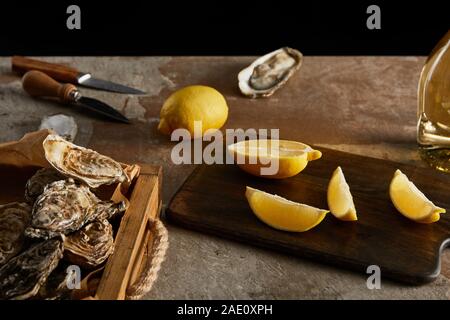 selective focus of delicious oysters in shells near lemons and knifes Stock Photo