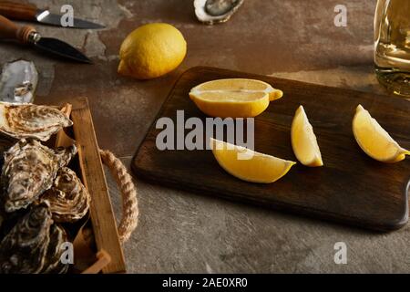 selective focus of delicious oysters in shells near lemons on wooden cutting board Stock Photo