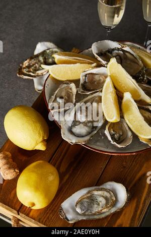 selective focus of whole lemons near oysters in bowl and champagne glasses on grey surface Stock Photo