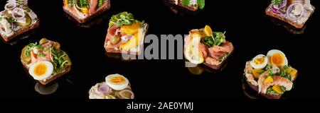 panoramic shot of rye bread with tasty danish smorrebrod sandwiches on black Stock Photo