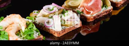panoramic shot of tasty smorrebrod sandwiches on black Stock Photo