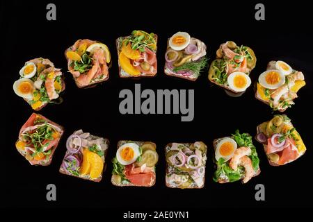 top view of rye bread with prepared danish smorrebrod sandwiches isolated on black Stock Photo