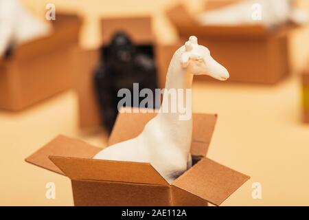 Selective focus of giraffe and toy animals in cardboard boxes on yellow background, animal welfare concept Stock Photo