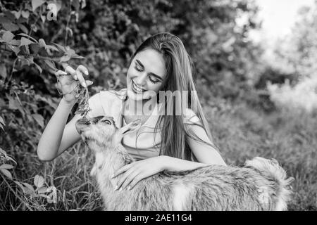 Woman and small goat green grass. Veterinarian occupation. Eco farm. Love and care. Animals law. Farm and farming concept. Village animals. Girl play cute goat. Feeding animal. Protect animals. Stock Photo